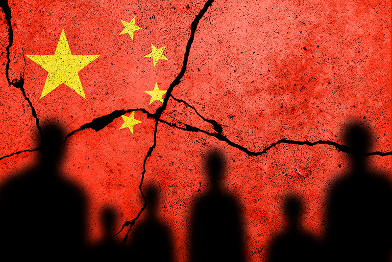 silhouettes of people against a cracked flag of China