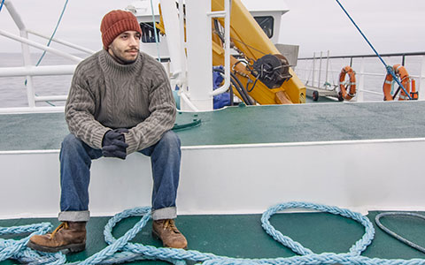 fisherman sitting on commercial fishing boat deck Photo Credit gorodenkoff