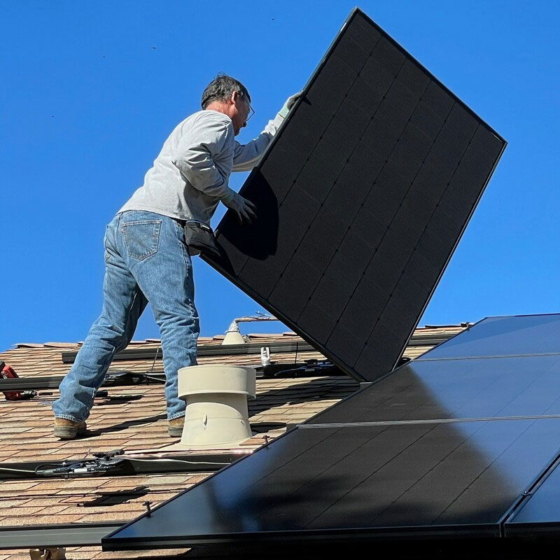 person on roof installing solar panels