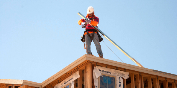 A roofer stands on a rooftop