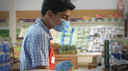 A teenage boy works as a cashier in a grocery store.