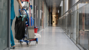 A custodian moves cleaning materials through a corridor.