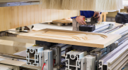 Close-up shot of a woodworking machine cutting a detailed design into a cabinet door. 