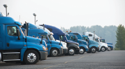 A line of large trucks in a parking lot. 