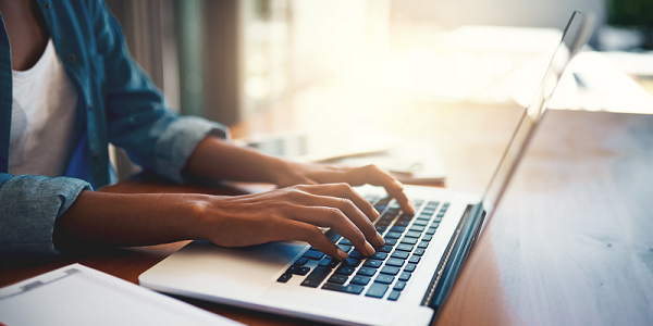 Close-up shot of a womans hands typing on a laptop.