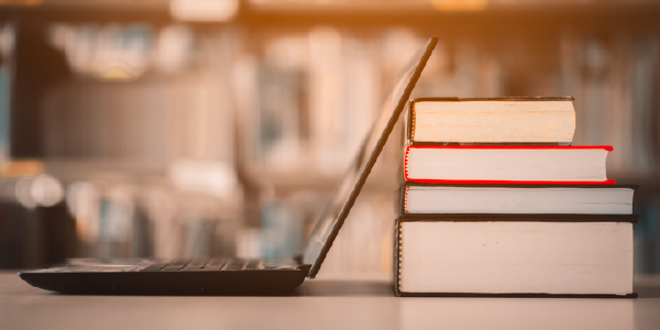 An open laptop and books sit on a table.