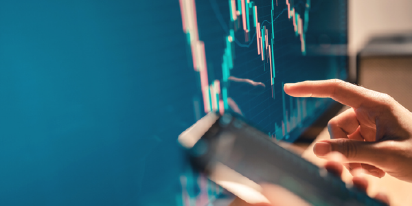 A womanâs hand traces a financial chart while she holds a cellphone in her other hand. 