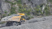 A large vehicle hauling stones at a mining site. 