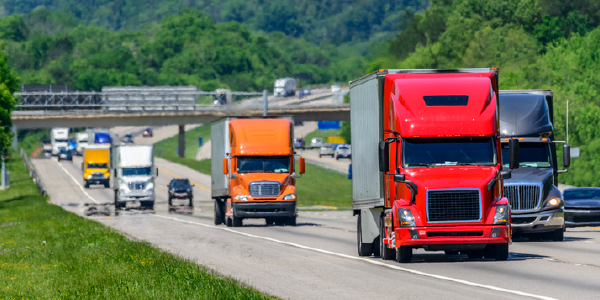 A steady flow of semis lead the way down a busy interstate highway. 