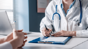 Close-up of a doctor writing on a clipboard.