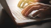 Close-up of hands entering information on a laptop.