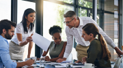 A diverse work team gathers at a conference table.