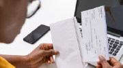 A woman removes a paycheck from an envelope.