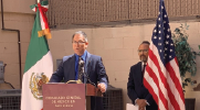 Wage and Hour Division Assistant District Director Jose Medina speaks at a podium in front of U.S. and Mexican flags.