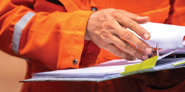 Close-up of person in a reflective orange jacket reviewing a binder.