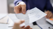 Close-up of a hand delivering a paycheck.