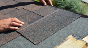 A roofer places tiles on a roof.