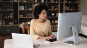 A woman typing on a computer while working from home. 