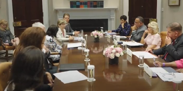 Secretary Walsh, Dr. Jill Biden and others sit around a long conference table in the White House. 