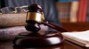 A gavel rests in front of a pile of law books. 