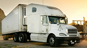 The sun sets behind a semi truck parked on a dirt road in the Southwest.