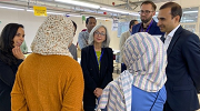 Thea Lee and other U.S. government officials engage in conversation on a garment factory floor with workers and business owners.