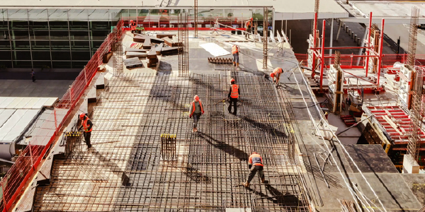 Construction workers in safety gear at a construction site viewed from above.