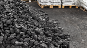 A large pile of coal near a stack of loaded pallets.