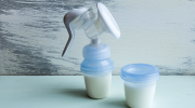 A manual breast pump with milk accessories sits on a table.