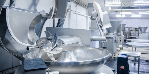 An industrial meat grinder with sharp blades in a meat processing facility. 