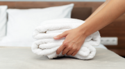 Close-up of hotel staff setting towels on a bed.