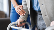 A careworker helps an older man use a walker