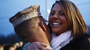 A woman embraces a man in a military uniform.