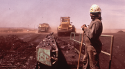 A Navajo worker at the Peabody Coal Co. in May 1972. They stand with their face covered watching heavy machinery as dust blows in the wind. Source: Environmental Protection Agency. https://catalog.archives.gov/id/544160