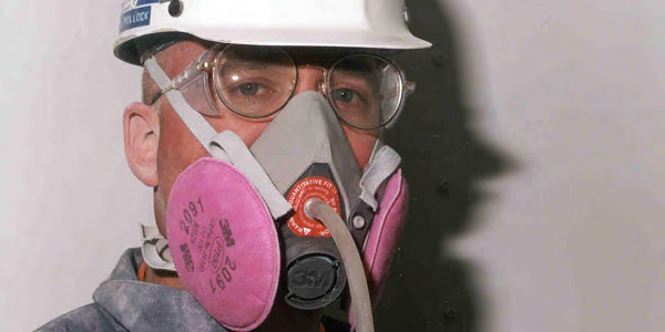 Close-up of a man wearing a helmet, safety goggles and respirator. 