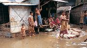 A family stands outside their home in Dhaka, Bangladesh, surrounded by floodwaters.
