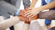 Four workers join hands in the center of a circle, symbolizing unity.