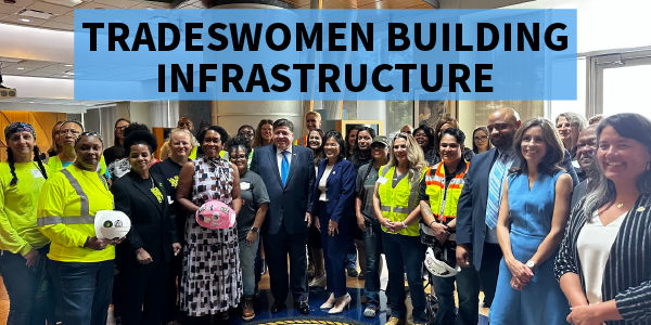 Acting Secretary Su, Illinois Gov. J.B. Pritzker and Lt. Gov. Juliana Stratton pose for a group photo with dozens of tradeswomen and colleagues, some in protective gear, some in suits.