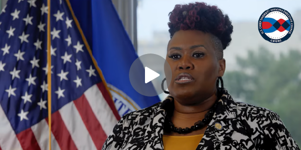 Screen grab of a video shows Alaysia Black Hacket addressing a camera while seated in front of an American flag.