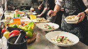 A close-up photo of several restaurant workers preparing food in a kitchen.