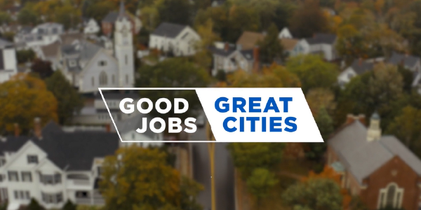 Good jobs. Great cities. Text appears over unfocused aerial shot of a small city's downtown, full of buildings and trees. 