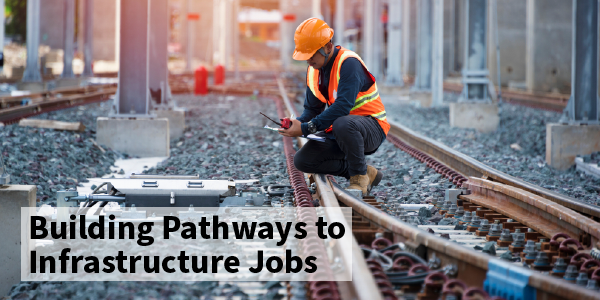 A railroad worker in safety gear crouched down by a railroad track. Text reads "Building pathways to infrastructure jobs"