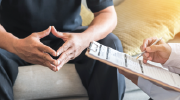 A man consults with a health professional who consults a clipboard.