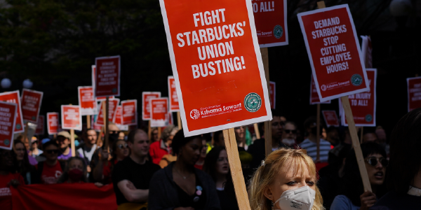 Photo from Seattle, Washington. Activists march at the Starbucks Worker Solidarity Rally in support of unionization for baristas and other retail workers, holding signs reading "Fight Starbucks' Union Busting."