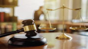 A judgeâs gavel lying alongside the scales of justice on a table. 