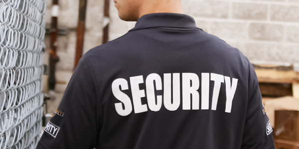 A security guard looking through a fence.