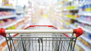 A grocery shopping cart with a blurred background of a supermarket aisle.