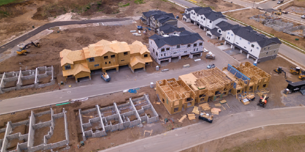 Aerial view of a housing development under construction shows houses in various states of completion.