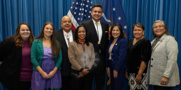 Acting Secretary Su stands with Tribal leaders in front of the American and Labor Department flags. 