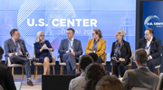 Thea Lee holds a microphone while speaking during a panel discussion with five other people during COP28. The backdrop says âU.S. Center, Dubai 2023.â